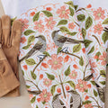 Floral and bird patterned fabric with brown gloves on a white background