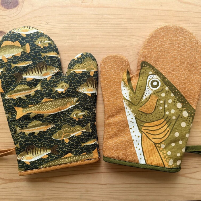 Pair of oven mitts with fish pattern on a wooden surface