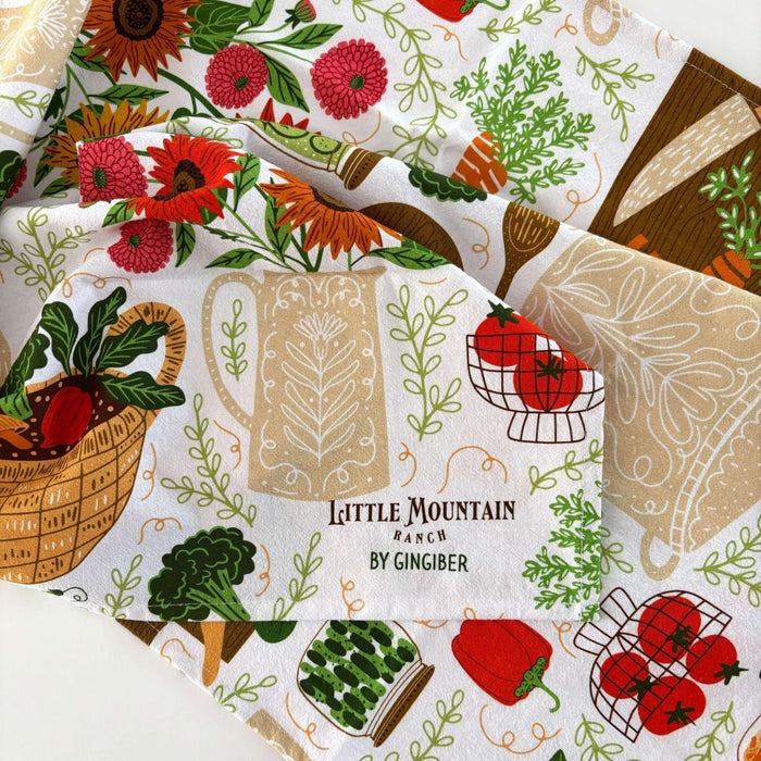 Patterned fabric with vegetables, a mug, and 'Little Mountain Ranch' branding.