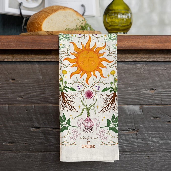 Decorative towel with sun and plant design hanging on a wooden surface