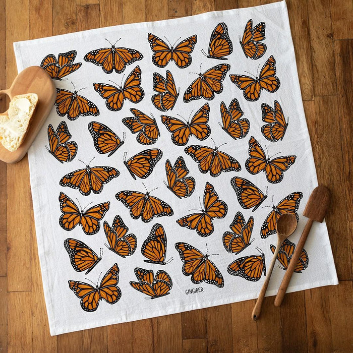 Butterfly-patterned towel on a wooden surface with bread and wooden spoons.