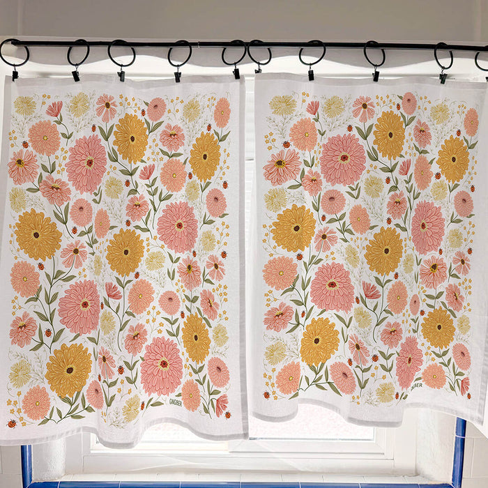 Floral patterned curtains hanging on a rod with a window in the background.